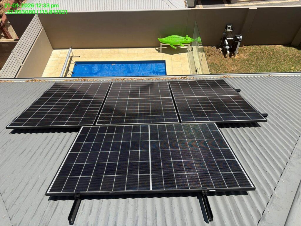 Four solar panels are installed on a corrugated metal roof in Bibra Lake. In the background, there is a swimming pool, a large green inflatable toy, and a small patio area enclosed by a glass fence. The home features 9.975kW solar with 50.5kWh battery storage.