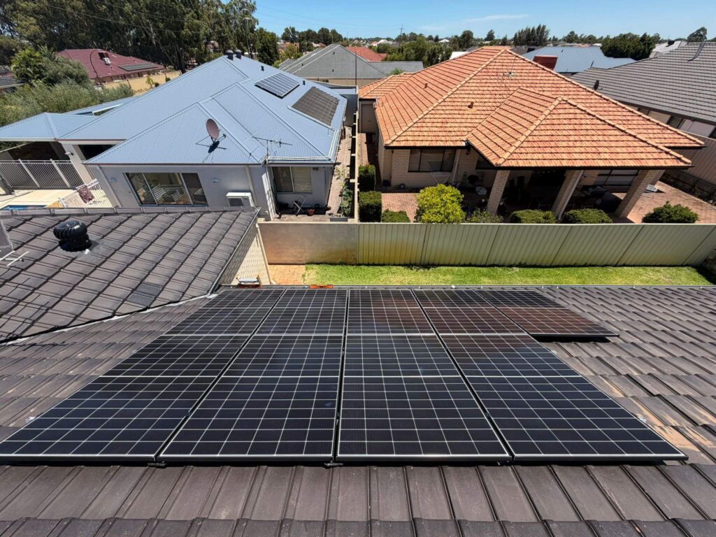 A 9.975kW solar system installed on a dark-tiled roof in Canning Vale, with neighbouring houses visible under a clear sky, is paired with 50.5kWh battery storage for efficient energy use in this suburban neighbourhood.