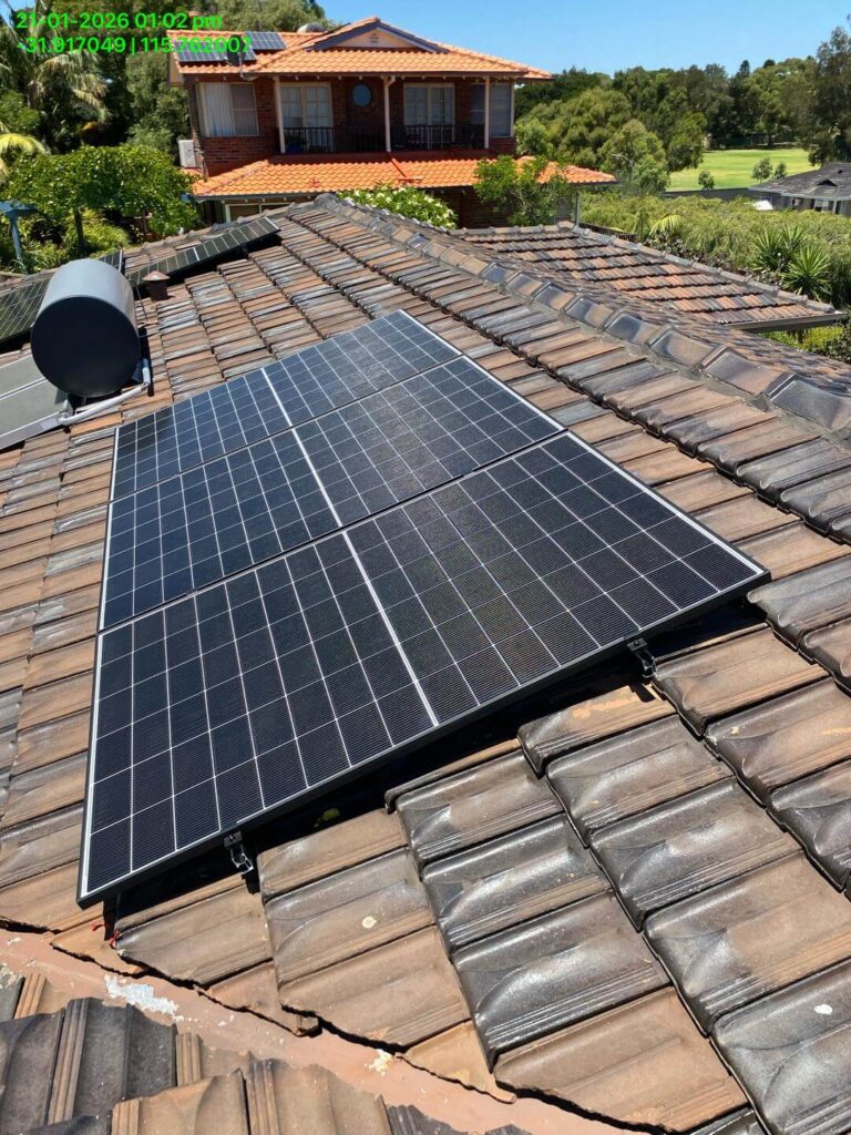 A set of solar panels, featuring a 15.75kW solar system with Sigenergy EC10TP and 24kWh storage, is installed on a tiled rooftop. Another house, greenery, and trees are visible in the background under a clear sky.
