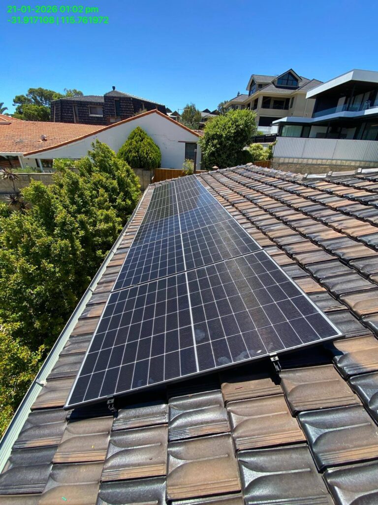 A row of solar panels, including a Sigenergy EC10TP system with 24kWh storage and 15.75kW solar capacity, is installed on a tiled rooftop in a residential area on a sunny day, with houses and trees visible in the background.
