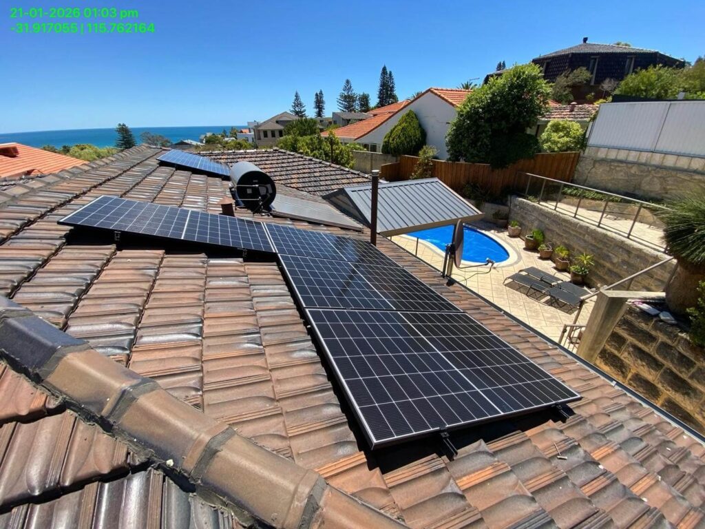 Rooftop solar panels, including a Sigenergy EC10TP system with 15.75kW solar and 24kWh storage, are installed on a tiled roof overlooking a back garden pool, nearby houses, lush greenery, and an ocean view in the background.