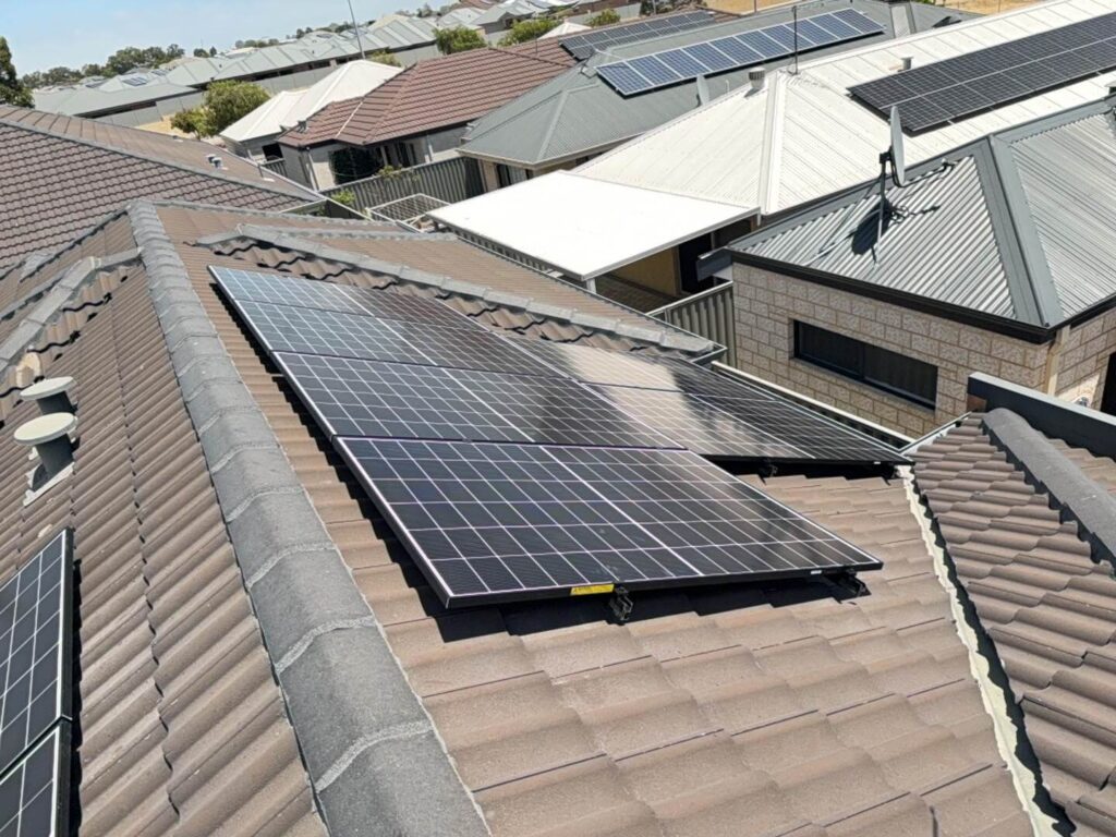 Solar panels installed on the tiled roof of a house in Harrisdale, with a 7.125 kW solar system and 40 kWh battery storage, surrounded by other homes—some also featuring solar panels on their roofs.