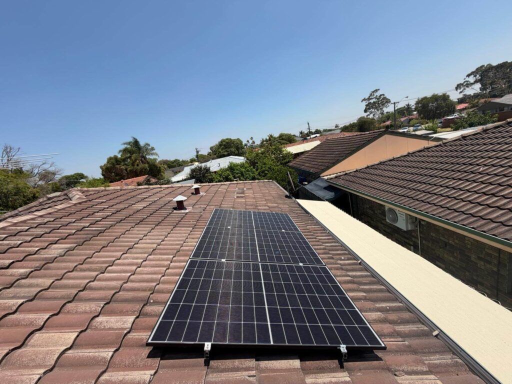 Solar panels installed on the brown-tiled roof of a Parkwood home, featuring a powerful 9.975kW solar system and 50.5kWh battery storage, under a clear blue sky with neighbouring houses and trees in the background.