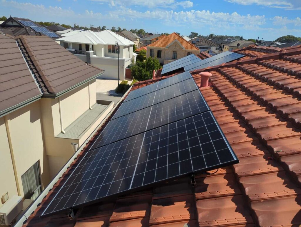 Solar panels and a Growatt battery storage system installed on a red-tiled residential rooftop in Stirling, with neighbouring houses visible under a partly cloudy sky.