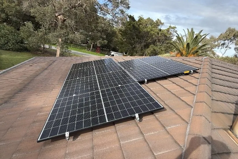 Trina solar panels on a tiled roof surrounded by gum trees in Falcon