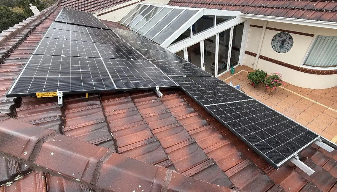 Solar panels on a terracotta roof beside a glass conservatory in Floreat