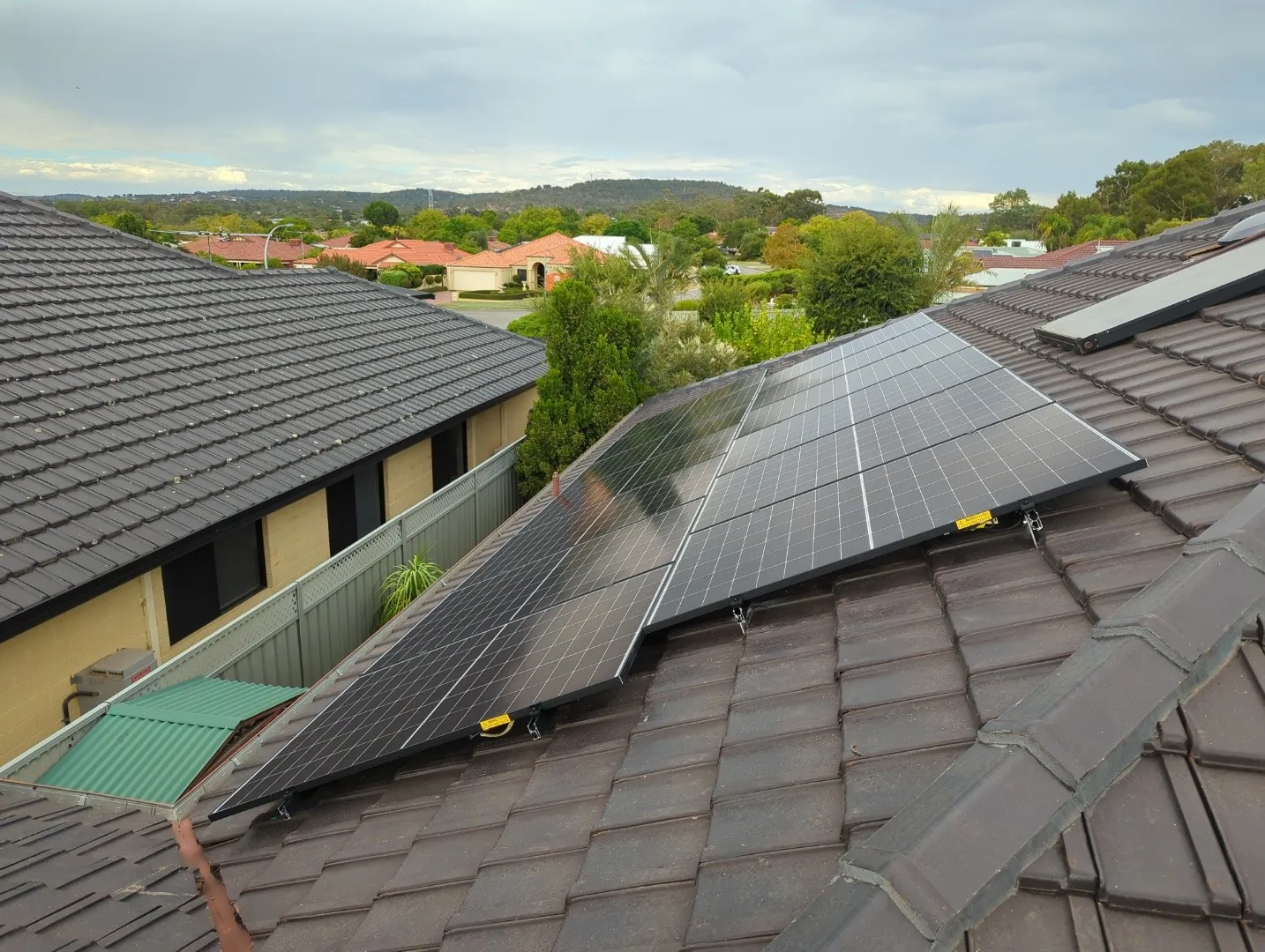 Solar panels on a tiled roof in Helena Valley with the Perth hills behind
