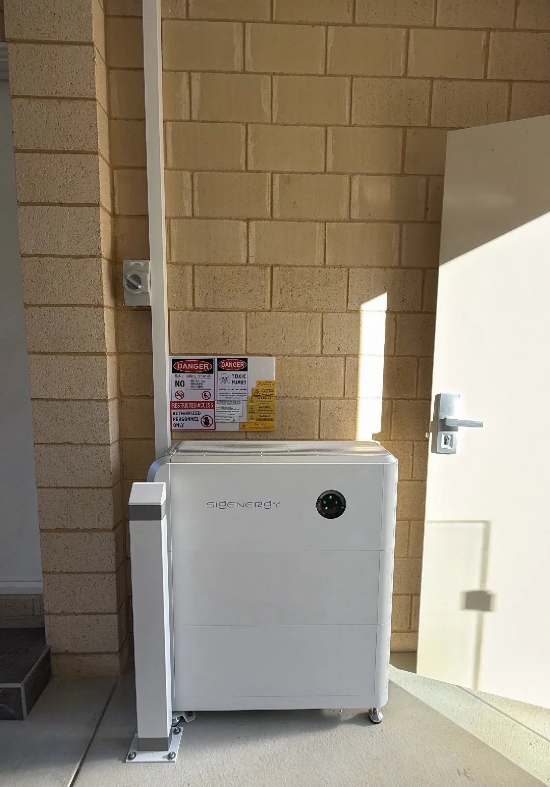 SigenStor battery installed under cover beside a side door